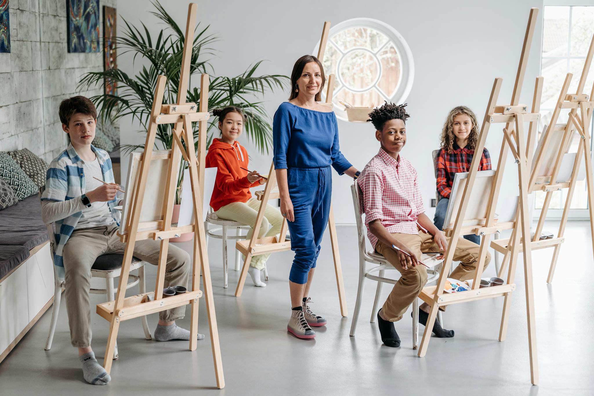 Children participating in a painting class with a teacher, fostering creativity and diversity.