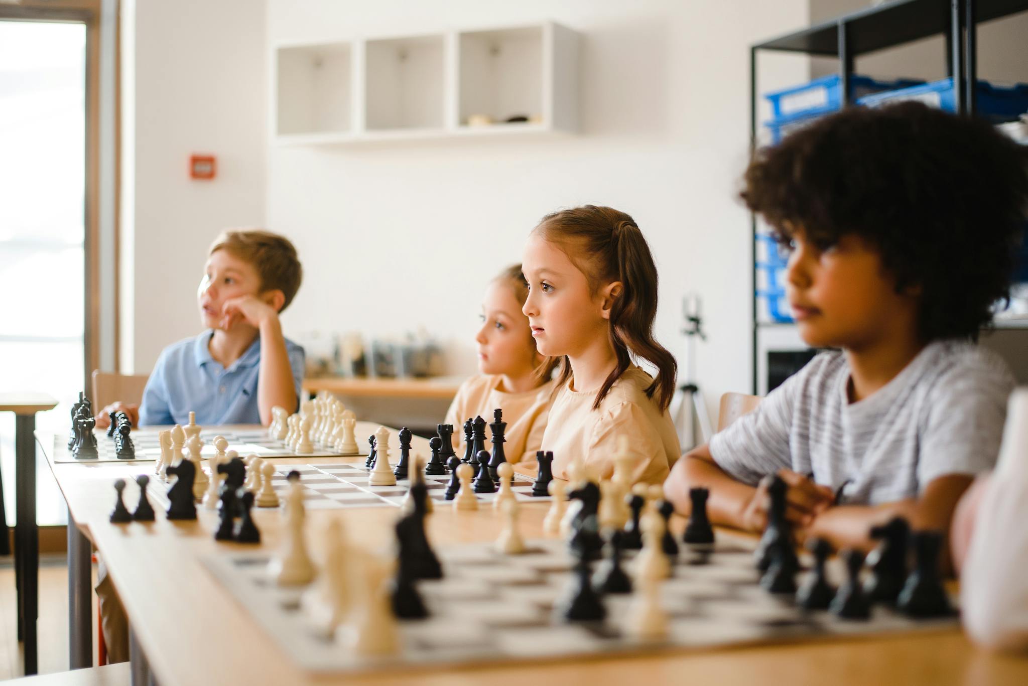 Kids focused on an intense chess game in a classroom, promoting strategic thinking.