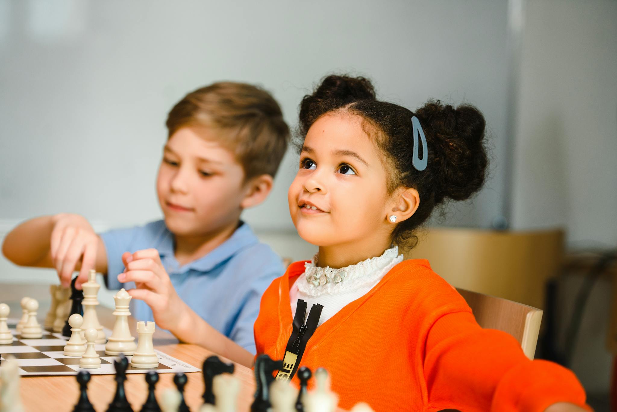 Two children learning and playing chess together indoors, fostering educational growth.