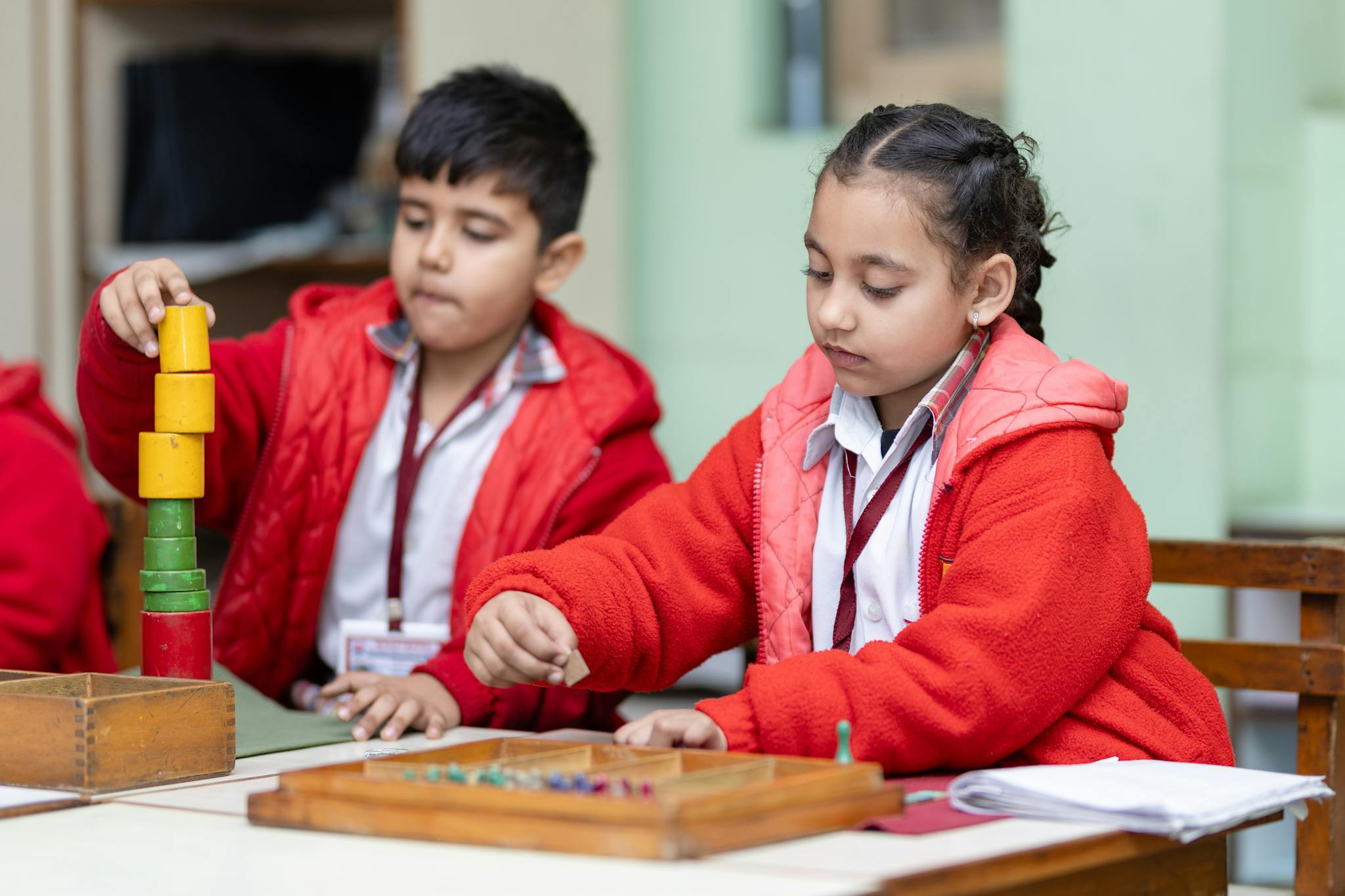 Two young children focus on educational activities at a classroom table.