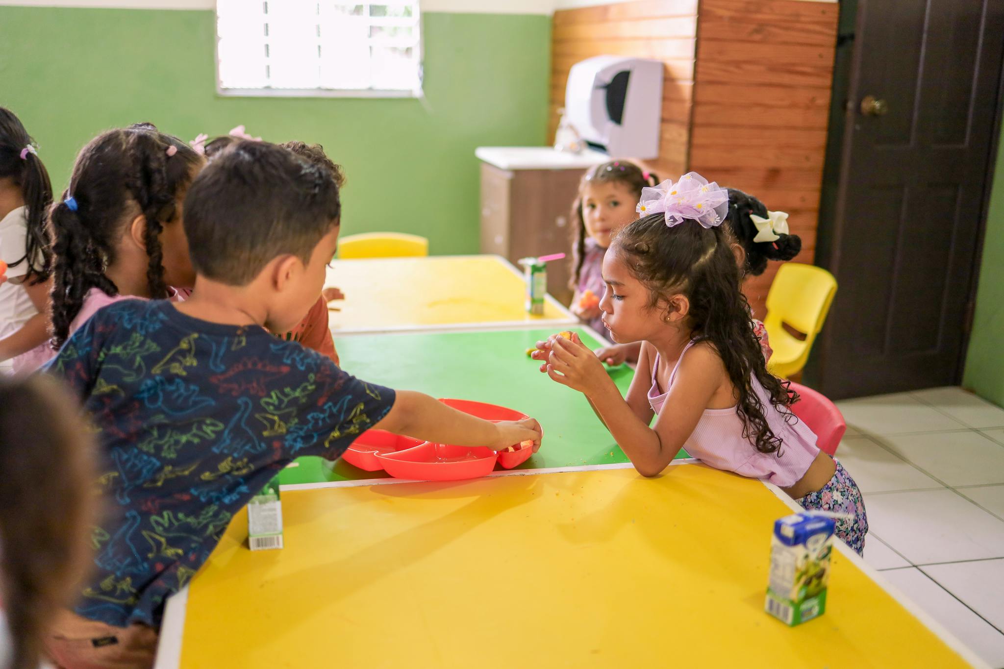 Más servicios Young children enjoying a collaborative learning activity in a colorful classroom setting.